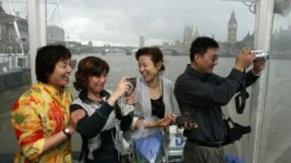 Turistas chinos toman fotograf&iacute;as durante su navegaci&oacute;n por el T&aacute;mesis de Londres.