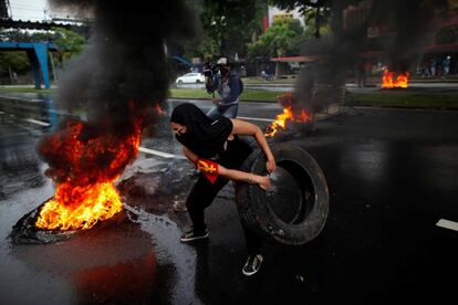 Una estudiante de la Universidad de Panamá (UP), carga una llanta para incendiarla durante una protesta en la vía Transísmica, en Ciudad de Panamá (Panamá).