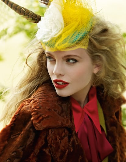 Tocado con red, flores y plumas de faisán de Mimoki. Chaqueta y blusa roja de seda con corbata de lazo, ambas piezas de Gucci.