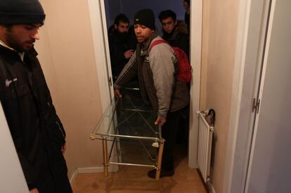 Un hombre traslada una mesa para colocarla en el pasillo, fuera de la vivienda, y bloquear la salida del ascensor.
