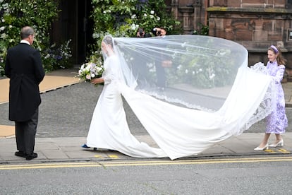 La novia ha tenido que luchar contra las fuertes ráfagas de viento para contener la larga cola del vestido y el velo a su entrada a la iglesia. El cortejo nupcial tuvo que detenerse unos minutos para sujetar las capas de tela. 