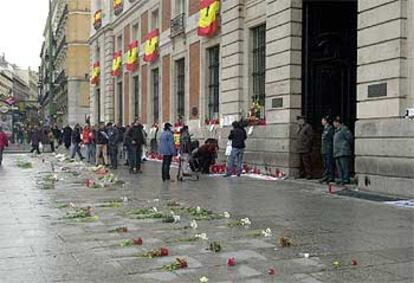 Los madrileños se acercan esta mañana a depositar flores y encender velas ante la sede del Gobierno de la comunidad.