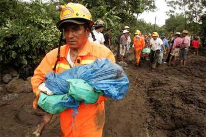 Un bombero lleva en brazos el cuerpo de un niño muerto en el desprendimiento de tierras en Panabaj.