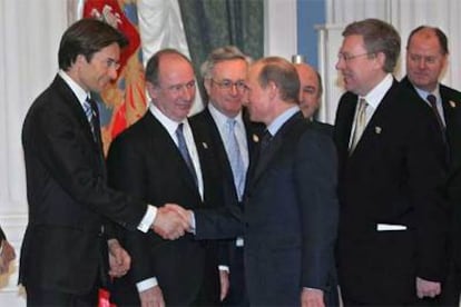 Vladímir Putin (derecha) estrecha la mano del ministro de Finanzas austriaco, en presencia de Rato (entre ellos).