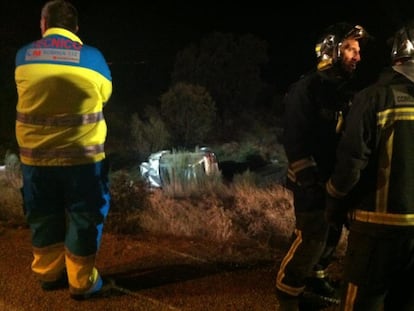 Un sanitario observa el todoterreno accidentado tras caer por el barranco de 10 metros. 