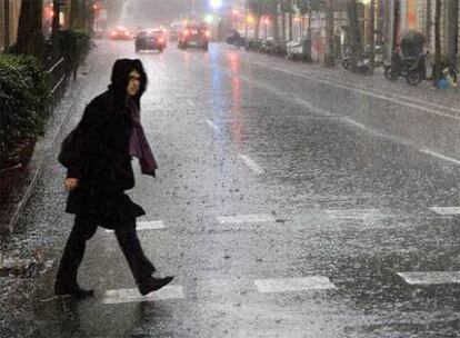 Una persona cruza una calle en pleno aguacero, ayer en el centro de Barcelona.