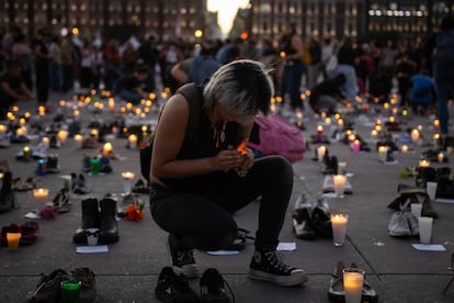 Una mujer enciende una veladora al caer la noche en el Zócalo.