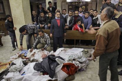 Dos hombres tapan los cadáveres de varias de las víctimas en el interior de la iglesia copta atacada ayer en Alejandría.