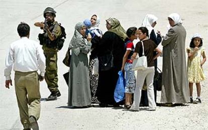 Un soldado israelí apunta a un hombre mientras la familia de éste aguarda para cruzar un control militar cerca de la ciudad de Hebrón.