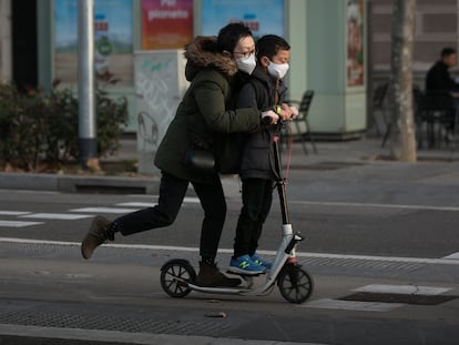 Dos jóvenes en patinete por paseo de Sant Joan, en Barcelona.