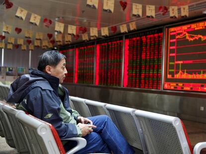 Un hombre observa un panel de información bursátil en Pekín (China).