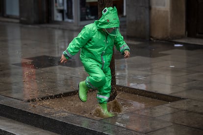 En la imagen, un niño juega en un charco de agua, formado por las lluvias del pasado mes de marzo, a los pies de un árbol en carretera de Sants (Barcelona).