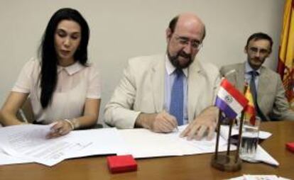 El presidente de la Cámara Oficial Española de Comercio, Industria y Servicios en Paraguay, Benito Barrera (c) y la presidenta de la Red Carolina en Paraguay, Diana Bernal (i), firman unos documentos junto al Encargado de Negocios de la Embajada de España, Pablo Desportes (d) este 18 de diciembre de 2013 en Asunción (Paraguay).