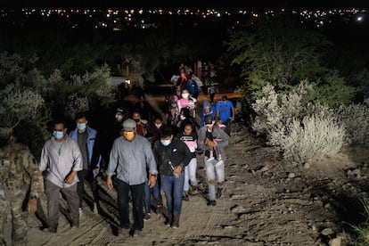 Solicitantes de asilo son escoltados por agentes estadounidenses tras cruzar el río Bravo, en la frontera con México.