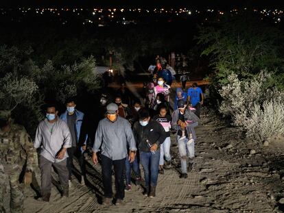 Solicitantes de asilo son escoltados por agentes estadounidenses tras cruzar el río Bravo, en la frontera con México.