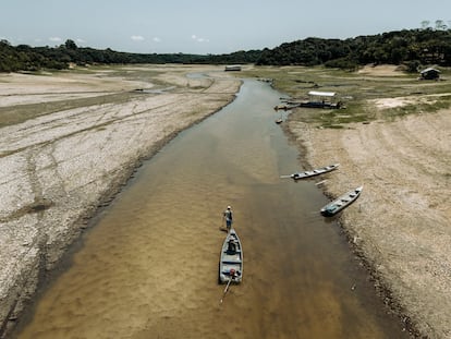 A man pulls a boat through the shallow center of a river near the community of São Francisco de Marina, which is cut off due to the low water levels of the local rivers.