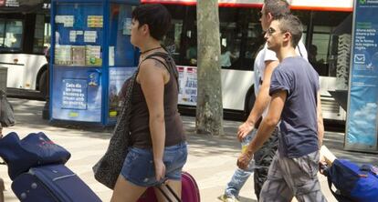 Varios turistas arrastran sus maletas hacia un hotel en las Ramblas de Barcelona.