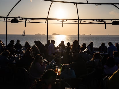 Un grupo de turistas disfrutan de la puesta de sol en una cala de Ibiza.