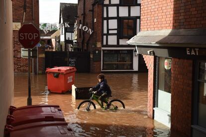 Un niño recorre en bicicleta una calle inundada en Hereford, al oeste de Inglaterra, tras la tormenta Dennis.