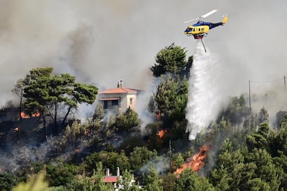 Un helicóptero de bomberos lanza agua mientras arde un incendio forestal en Varnava, cerca de Atenas, este domingo.