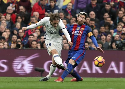 Luka Modric, del Real Madrid, (izquierda) lanza el balón con la presión de Lionel Messi, del FC Barcelona.
