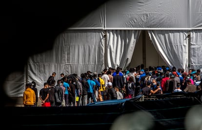 Migrantes del campo oficial de Las Raíces, Tenerife, hacen cola para recibir la comida. 