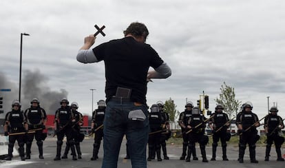 Un residente de Minneapolis, que se negó a ser identificado, sostiene una cruz mientras bloquea elpaso a los agentes de policía, este miércoles.