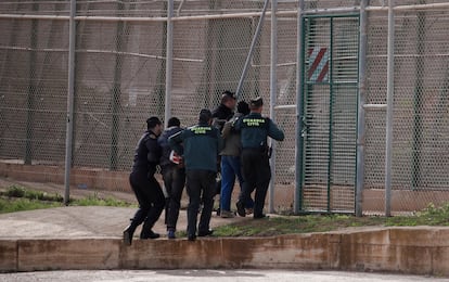 Agentes de la guardia civil preceden a expulsar por la valla a dos migrantes que acababan de saltar la valla de Melilla, en 2014.