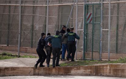 Agentes de la guardia civil preceden a expulsar por la valla a dos migrantes que acababan de saltar la valla de Melilla, en 2014.