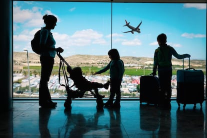 Una madre espera con sus hijos a embarcar en una terminal de un aeropuerto.