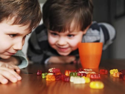 Duas crianças olhando ansiosas para doces. 