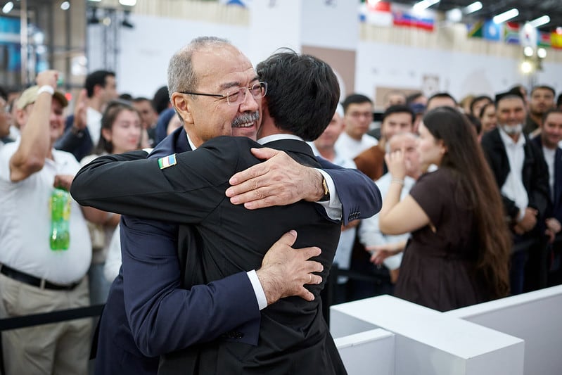 El primer ministro de Uzbekistán, Abdulá Arípov, abraza al cuarto tablero de la selección, Mujidin Madamínov, tras su victoria decisiva para lograr el oto