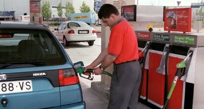 Un empleado de una gasolinera pone carburante en un vehículo.