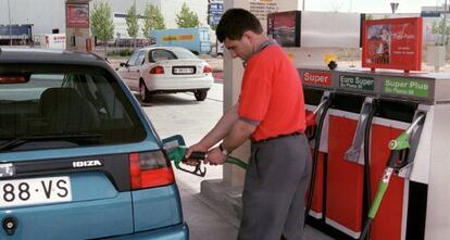 Un empleado de una gasolinera pone carburante en un veh&iacute;culo.