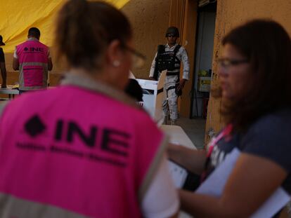 Un miembro del Ejército Mexicano reguarda a trabajadores del Instituto Nacional Electoral en Ciudad Juárez.