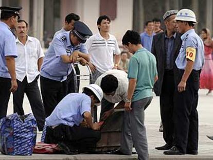 Policías chinos registran las maletas de ciudadanos uigures en Kashgar, en la región de Xinjiang.