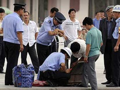 Policías chinos registran las maletas de ciudadanos uigures en Kashgar, en la región de Xinjiang.