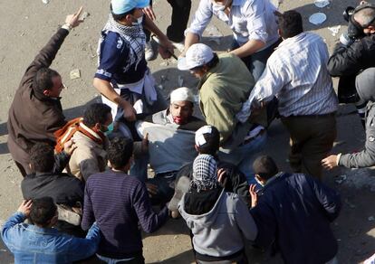 Unos manifestantes socorren a un herido durante los disturbios en la Plaza de Tahrir