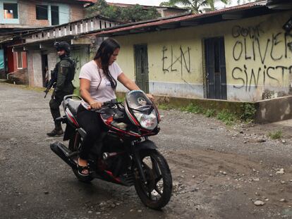 Una mujer conduce una motocicleta junto a una casa con pintadas alusivas al ELN y al Frente Oliver Sinisterra, el 9 de septiembre de 2022, en Tumaco.