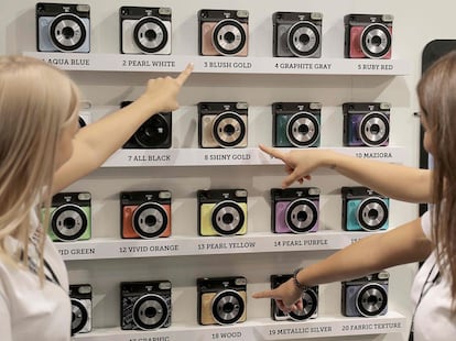 Dos trabajadores señalan las cámaras Fujifilm Instax Square SQ6, el 25 de septiembre de 2018, en Photokina.  