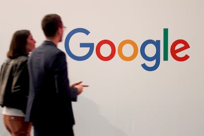 Dos personas pasan ante el logotipo de Google en un encuentro de empresas tecnológicas en París.