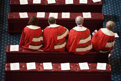 Un grupo de personas permanece en su sitio correspondiente en la Cámara de los Lores del Parlamento británico antes del inicio del discurso de la reina Isabel II.