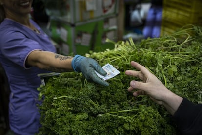 Una vendedora entrega un billete en una plaza de mercado en Bogotá, el 30 de marzo de 2023.