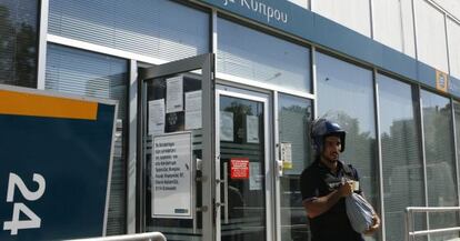 Un guardia saca dinero de una oficina del Bank of Cyprus.