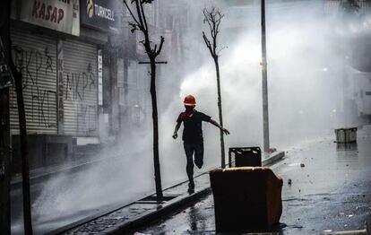 Un manifestante huye cuando la policía antidisturbios turcos usan cañones de agua para dispersar a los manifestantes durante una manifestación contra el reciente accidente de la mina en Soma.