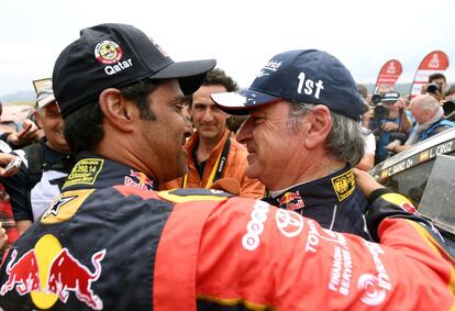 El piloto español Carlos Sainz es felicitado por el piloto Nasser Al-Attiyah después de llegar a meta.