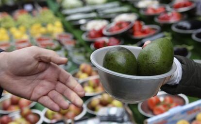 Un cliente compra aguacates en un mercado. 