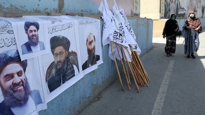 Dos afganas pasan junto un puesto de venta de banderas y carteles con la imagen de líderes talibanes el jueves en Kabul.