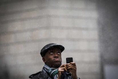 Un hombre hace fotos con su movil a la nieve que cae sobre Manhattan, Nueva York