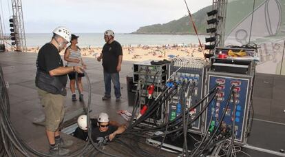 Varios operarios dan los últimos retoques al escenario de la playa de la Zurriola.